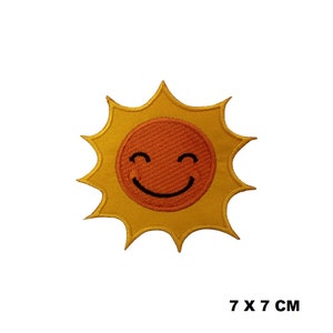 May include: Embroidered patch with a smiling sun design. The sun has a textured orange centre with a black smiling face, surrounded by yellow rays. The patch measures 7 x 7 cm.