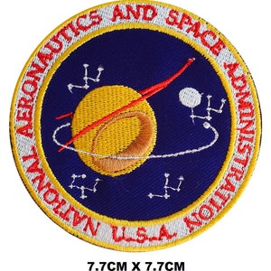 Puede incluir: Un parche bordado azul y amarillo con el texto "National Aeronautics and Space Administration" y "USA" alrededor de una imagen estilizada de un planeta y un cohete. El parche mide 7,7 cm por 7,7 cm.