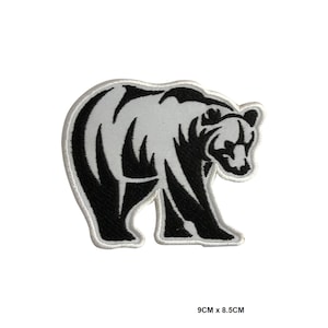 May include: Black and white embroidered iron-on patch of a bear walking. The bear is stylized with a tribal design. The patch is 9 cm by 8.5 cm.