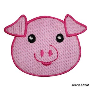 May include: A pink embroidered pig face patch. The pig has black eyes, a pink snout, and a smiling mouth. The patch measures 7cm x 5.5cm.