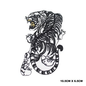 May include: Embroidered patch depicting a black and white tiger with an open mouth and yellow teeth. The tiger is in a dynamic pose, ready to pounce. The patch measures 10.5cm by 6.5cm.