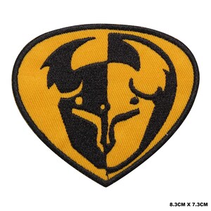 May include: A shield-shaped embroidered patch featuring a split design of black and yellow colours. The graphic depicts a stylised bull head silhouette in black on a yellow background and yellow on a black background. The patch measures 8.3 cm x 7.3 cm.