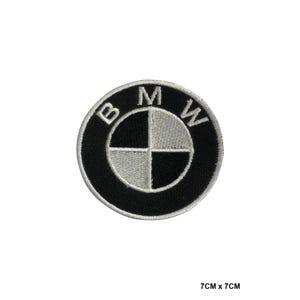 May include: Embroidered patch featuring the BMW logo. The circular patch has a black border with the letters "B", "M", and "W" in white. The center is divided into four quadrants of black and silver. The patch measures 7cm x 7cm.