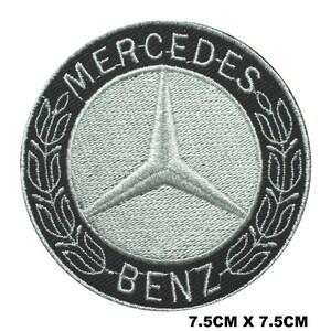 May include: A round, embroidered patch featuring the Mercedes-Benz logo. The patch is 7.5cm x 7.5cm (approximately 3 inches x 3 inches). The design includes a silver three-pointed star within a silver circle, surrounded by a black border with the words "MERCEDES-BENZ".