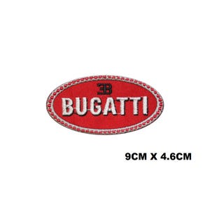 Könnte beinhalten: Ovaler, rot gestickter Aufnäher mit dem Wort "BUGATTI" in weißen Großbuchstaben. Der Aufnäher hat einen weißen Rand und das Bugatti-Logo. Der Aufnäher misst 9 cm x 4,6 cm.