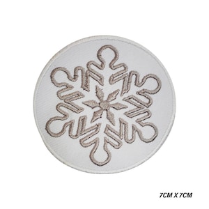 May include: A circular, white embroidered patch with a grey snowflake design. The patch is 7cm x 7cm. The snowflake is detailed, suitable for winter crafts or clothing embellishments.
