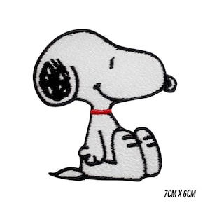 Könnte beinhalten: Gestickter Aufnäher mit Snoopy aus Peanuts, in sitzender Position. Der Aufnäher ist weiß mit schwarzen Umrissen und Details, einschließlich Snoopy's Ohren, Augen und Nase. Ein rotes Halsband ist um seinen Hals. Der Aufnäher misst 7 cm x 6 cm.