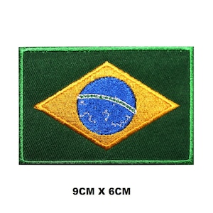Puede incluir: Parche bordado para planchar con la bandera de Brasil. La bandera es verde con un diamante amarillo en el centro. Dentro del diamante hay un círculo azul con una banda blanca. El parche mide 9 cm por 6 cm.