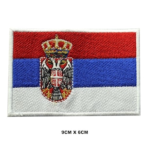 May include: Embroidered patch of the Serbian flag. The flag is red, blue, and white with a coat of arms in the center. The patch is 9 inches by 6 inches.