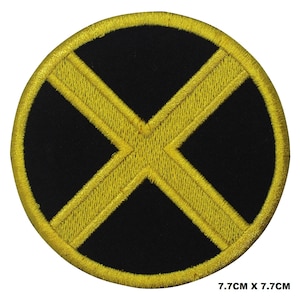 Peut inclure: Un écusson brodé noir et jaune avec un grand X jaune au centre. L'écusson est circulaire et mesure 7,7 cm de diamètre.