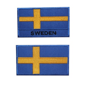 Peut inclure: Deux patchs brodés représentant le drapeau suédois. Le patch du haut porte le mot "SUÈDE" sous le drapeau. Les deux patchs sont bleus avec une croix jaune.