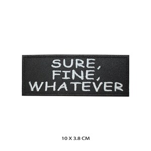 May include: A black rectangular patch with white embroidered text that reads "SURE, FINE, WHATEVER." The patch measures 10 cm long by 3.8 cm wide. The patch is a simple, yet bold statement piece.