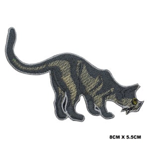 Peut inclure: Écusson brodé représentant un chat gris stylisé avec des rayures beiges, le dos courbé et des yeux jaunes. Le patch mesure 8 cm x 5,5 cm. Le chat est représenté dans une pose ludique, regardant vers le bas. Le patch a une bordure blanche.