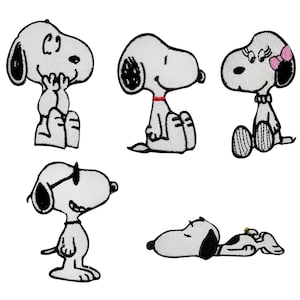 Op de afbeelding: Een verzameling van vijf Snoopy-patches in verschillende poses. De patches zijn wit met zwarte accenten en tonen Snoopy in verschillende stemmingen en outfits, waaronder een met een zonnebril en een met een roze strik.