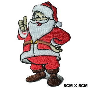 May include: Embroidered iron-on patch featuring a red and white Santa Claus giving a thumbs up. The patch is 8 cm by 5 cm.