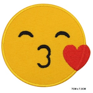 Puede incluir: Parche amarillo bordado para planchar con una carita sonriente que lanza un beso con un corazón rojo. El parche mide 7 cm por 7,3 cm.