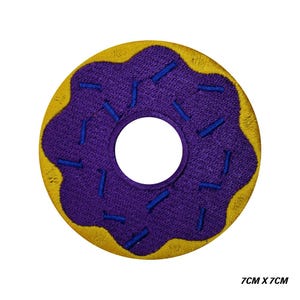 May include: Embroidered donut patch. The patch features a purple iced top with blue sprinkles and a yellow base. The patch measures 7cm x 7cm.