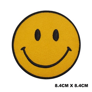 May include: Yellow smiley face iron-on patch with a black outline. The patch is 8.4 cm by 8.4 cm.