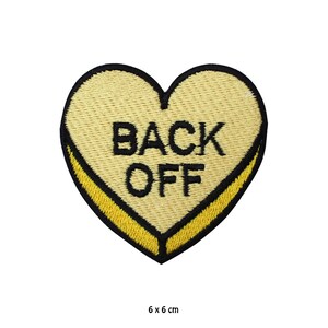 Peut inclure: Patch en forme de cœur jaune avec une broderie noire qui dit "BACK OFF". Le patch mesure 6 cm sur 6 cm.