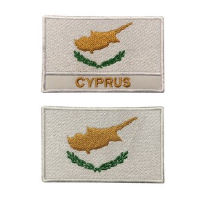 May include: Two white embroidered patches with the flag of Cyprus. The top patch has the word "CYPRUS" below the flag.