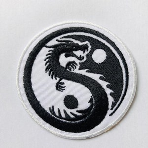 May include: Black and white embroidered patch featuring a yin yang symbol with a dragon wrapped around it. The patch is 7 cm by 7 cm.