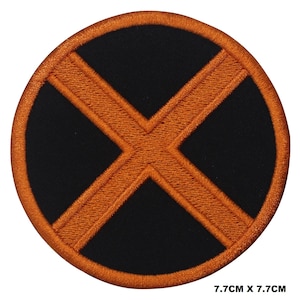 Op de afbeelding: Een ronde, geborduurde patch in zwart en oranje met een 'X'-ontwerp. De patch heeft een diameter van 7,7 cm.