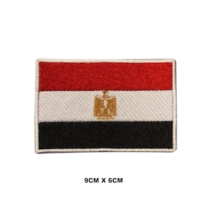 May include: An embroidered patch of the Egyptian flag. The flag is red, white, and black with a gold eagle in the center. The patch is 9 cm by 6 cm.