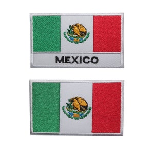 May include: Two embroidered patches featuring the Mexican flag. The flag is green, white, and red with the Mexican coat of arms in the centre. The patches have a white border and the word "MEXICO" is printed below the flag on the top patch.