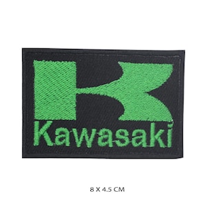 May include: A rectangular embroidered patch featuring a black background with a bright green Kawasaki logo and text. The design includes the stylized K emblem above the word Kawasaki in green thread. The patch measures 8 x 4.5 cm.