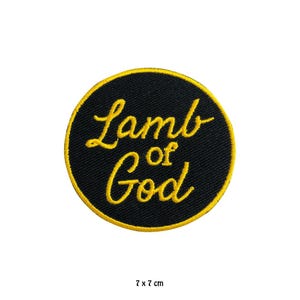 May include: A circular embroidered patch with a black background and a bright yellow border. The text "Lamb of God" is stitched in yellow cursive lettering across the centre. The patch measures 7 cm by 7 cm as indicated by the text below.