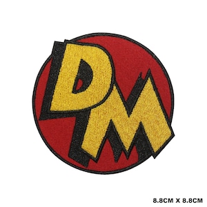 May include: A circular embroidered patch featuring the letters DM in yellow with a thick black outline, set against a solid red background. The patch measures 8.8 cm by 8.8 cm, which is approximately 3.46 inches by 3.46 inches in total size.