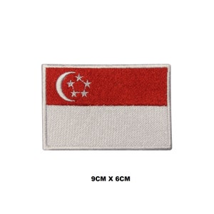 Puede incluir: Un parche bordado blanco y rojo con la bandera de Singapur. La bandera tiene una luna creciente y cinco estrellas en la esquina superior izquierda. El parche mide 9 cm por 6 cm.