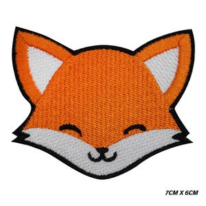 Könnte beinhalten: Gestickter Aufnäher mit einem lächelnden Fuchskopf. Der Fuchs hat orangefarbenes Fell, weiße Innenohren und Schnauze sowie eine schwarze Umrandung. Der Aufnäher misst 7 cm x 6 cm.