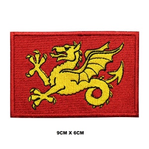 May include: Red embroidered patch with a gold dragon on a red background. The dragon is facing right and has wings spread. The patch measures 9 cm by 6 cm.