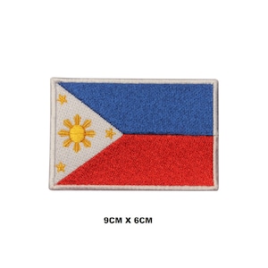 Puede incluir: Parche bordado de la bandera de Filipinas. La bandera es blanca con un triángulo azul en el asta y un campo rojo. El triángulo presenta un sol amarillo con ocho rayos y tres estrellas de cinco puntas. El parche mide 9 cm por 6 cm.