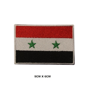 May include: An embroidered patch of the Syrian flag. The flag is red, white, and black with two green stars in the centre. The patch is 9 cm by 6 cm.