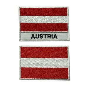 May include: Two embroidered patches featuring the Austrian flag. The top patch has the word "AUSTRIA" written below the flag. Both patches have a white border.