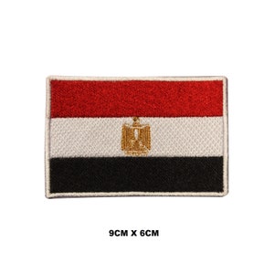 May include: An embroidered patch of the Egyptian flag. The flag is red, white, and black with a gold eagle in the center. The patch is 9 cm by 6 cm.