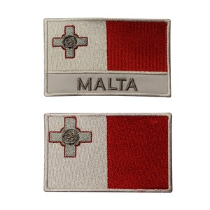 Może przedstawiać: Dwa haftowane naszywki z flagą Malty. Górna naszywka ma napis "MALTA" wydrukowany pod flagą. Obie naszywki są białe z czerwonym paskiem i białym krzyżem z małym kółkiem w środku.