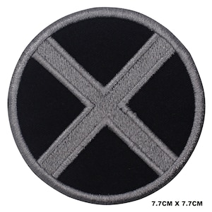 May include: A black and grey embroidered patch with an X shape in the centre. The patch is 7.7 cm in diameter.