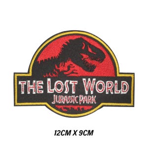 Peut inclure: Écusson brodé avec le texte "THE LOST WORLD JURASSIC PARK" en blanc sur fond noir. Une silhouette de dinosaure rouge est au-dessus du texte, sur fond rouge. Le patch mesure 12 cm x 9 cm.