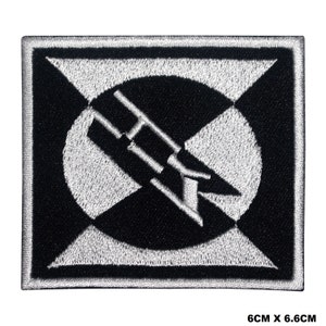 May include: Black and white embroidered patch featuring a stylised design of a rocket ship within a circle. The patch measures 6.6 cm by 6.6 cm.