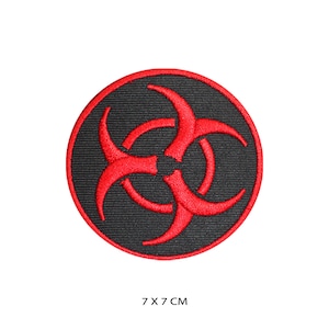 Puede incluir: Un parche circular negro con un símbolo de riesgo biológico rojo bordado. El parche mide 7 cm de diámetro.