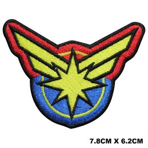 May include: An embroidered patch featuring a yellow eight-pointed star centred on a blue circular background, framed by red and yellow wing-like shapes with a black border. The patch measures 7.8 cm by 6.2 cm, as indicated by the text.