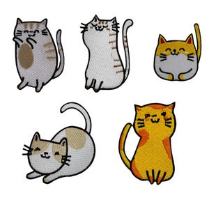 Op de afbeelding: Set van vijf geborduurde kattenpatches in verschillende poses. De katten hebben verschillende kleuren, waaronder grijs, wit en oranje, met zwarte contouren en lachende gezichten. Deze patches zijn ideaal om kleding of accessoires een vleugje vrolijkheid te geven.