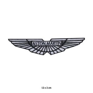 May include: Embroidered Aston Martin logo patch, a winged emblem with the brand name in a central rectangle. The patch is white with black detailing and measures 12 cm x 3 cm.