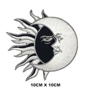 May include: A black and white embroidered patch featuring a sun and moon design. The sun has a stylised face with a single eye and the moon is a crescent shape. The patch measures 10 cm by 10 cm.