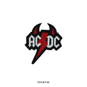 Op de afbeelding: Een geborduurde patch met het AC/DC-logo in witte letters, een centrale rode bliksemschicht en twee rode duivelshoorns op een zwarte achtergrond. De patch meet 7,2 x 6,7 cm, zoals aangegeven door de tekst onder het object.