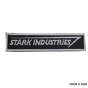 May include: A rectangular embroidered patch featuring a black background with a white border and the white text STARK INDUSTRIES. The design includes a stylised arrow graphic extending from the letter S. The patch measures 10 cm by 2 cm.