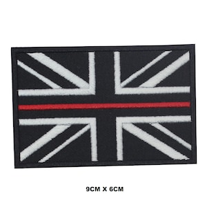 May include: Black and white embroidered Union Jack flag patch with a thin red stripe across the middle. The patch is 9 cm by 6 cm.